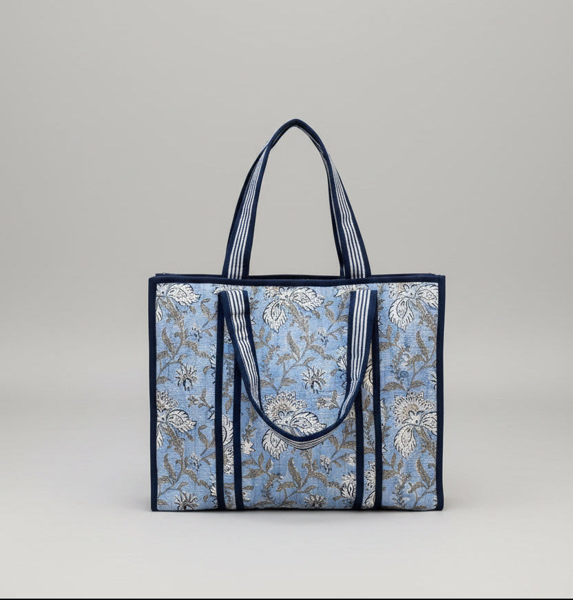 Floral patterned tote bag with blue straps on a light blue background 
