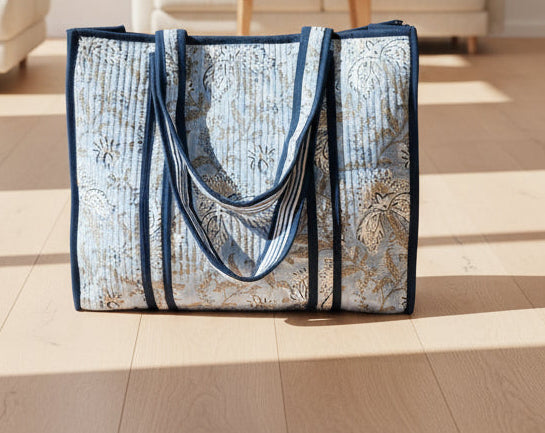 Light blue block printed quilted tote bag with dark blue straps.