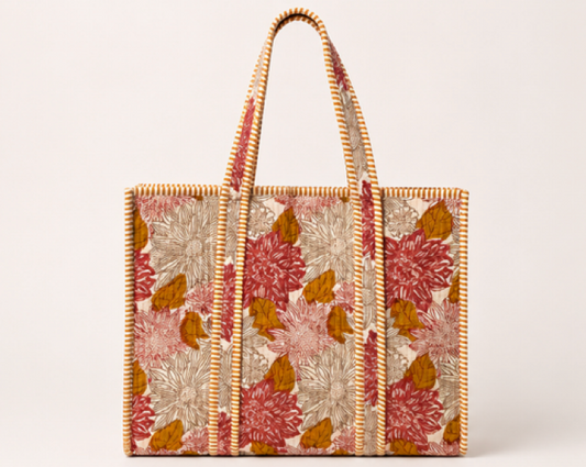A woven tote bag with a floral pattern in dusty pink, rust red, and ochre brown on a cream background, featuring natural orange rope handles and trim.
