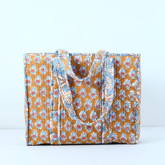 Indigo blue botanical hand block-printed quilted cotton tote bag hanging on rustic door